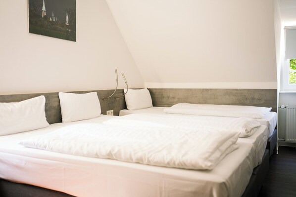 A bedroom with two beds, a view of a church, and a radiator.