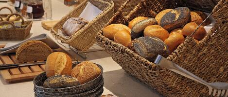 A variety of breads and pastries displayed in wicker baskets on a countertop.