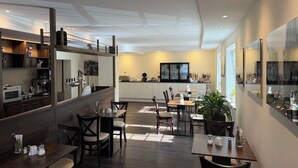 A modern restaurant with a bar area, dining tables, chairs, and a kitchen in the background. - Hotel Stadt Kamen (Kamen)