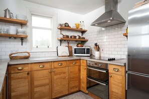 Una cocina moderna con armarios de madera, un refrigerador de acero inoxidable y un microondas.