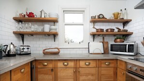 Eine Küche mit Holzausstattung, einer Mikrowelle, einem Toaster und Regalen mit Geschirr und Küchenutensilien.