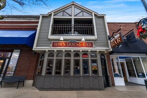 A two-story building with a sign reading 'Town House Bar' and 'Row House Bar' on the upper level. - Downtown Charlevoix Balcony Loft | Walk to Bridge St, Dining & Marina (Charlevoix)