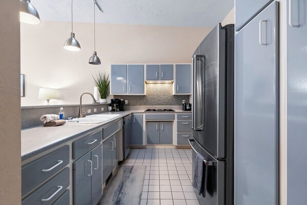 A modern kitchen with grey cabinets, stainless steel appliances, and pendant lighting. - Downtown Charlevoix Balcony Loft | Walk to Bridge St, Dining & Marina (Charlevoix)