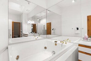 A modern bathroom with a large mirror, two sinks, and a bathtub. - Downtown Charlevoix Balcony Loft | Walk to Bridge St, Dining & Marina (Charlevoix)