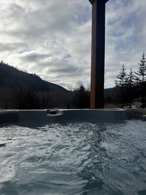 Ein Whirlpool mit Wasser, umgeben von bewaldeter Landschaft und einem bewölkten Himmel.