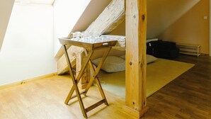 A room with a sloped ceiling, wooden beams, a window, and a wooden table. - Apartment 5 - Abendträumerei - Holiday apartment with loft in the count's forester's lodge (Temmen-Ringenwalde)