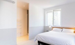 Ein Schlafzimmer mit einem Bett, einem Fenster und einer Heizung.