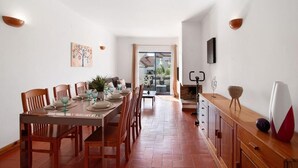 A dining area with a wooden table set for four, flanked by chairs, with a view to an outdoor patio. - Spacious apartment in the heart of Albufeira (Albufeira)