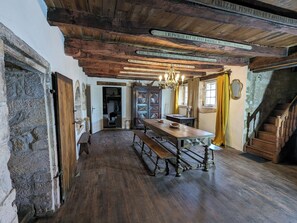 Une pièce rustique avec une table et des bancs en bois, un mur en pierre et un escalier.
