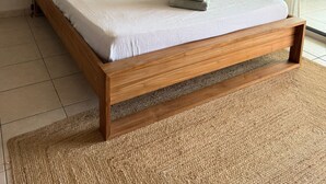 A bedroom with a wooden bed, two pillows, a bedside lamp, and two framed artworks on the wall. - Spacious  studio in peaceful Fort-de-France with AC (Fort-de-France)