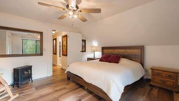 A bedroom with a wooden bed, a ceiling fan, a nightstand, and a dresser.