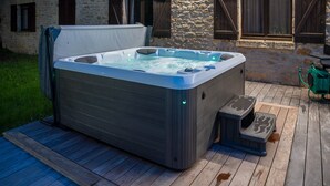 A hot tub on a wooden deck with a stone building in the background. - Swimming pool and jacuzzi – 4 adults, 4 children (Montignac)