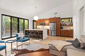 A modern kitchen with a central island, bar stools, and a large refrigerator.