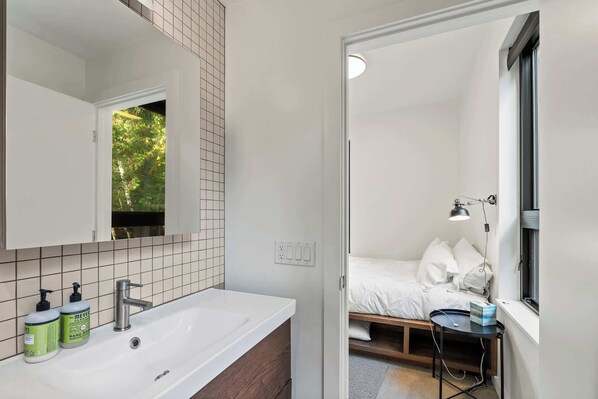 A modern bathroom with a large mirror, white sink, and two bottles of hand soap.