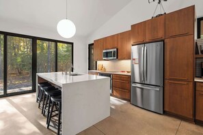 A modern kitchen with a central island, stainless steel appliances, and wooden cabinets.