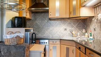 A modern kitchen with wooden cabinets, a stainless steel range hood, and a tiled backsplash.