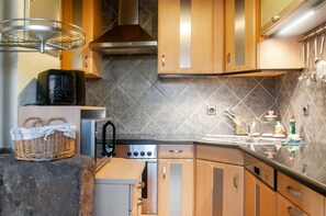 Une cuisine moderne avec des meubles en bois, une hotte de cuisson en acier inoxydable et un dosseret carrelé.