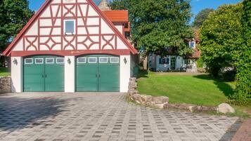 Un bâtiment traditionnel à colombages, avec deux portes vertes et un mur de pierre à l’avant.