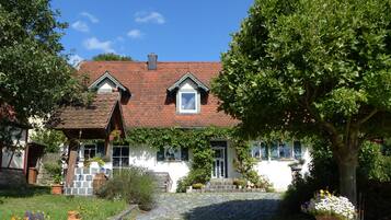 Ein traditionelles Haus mit einem Ziegeldach, einer Steintreppe, die zum Eingang führt, und einem Garten mit Blumentöpfen.