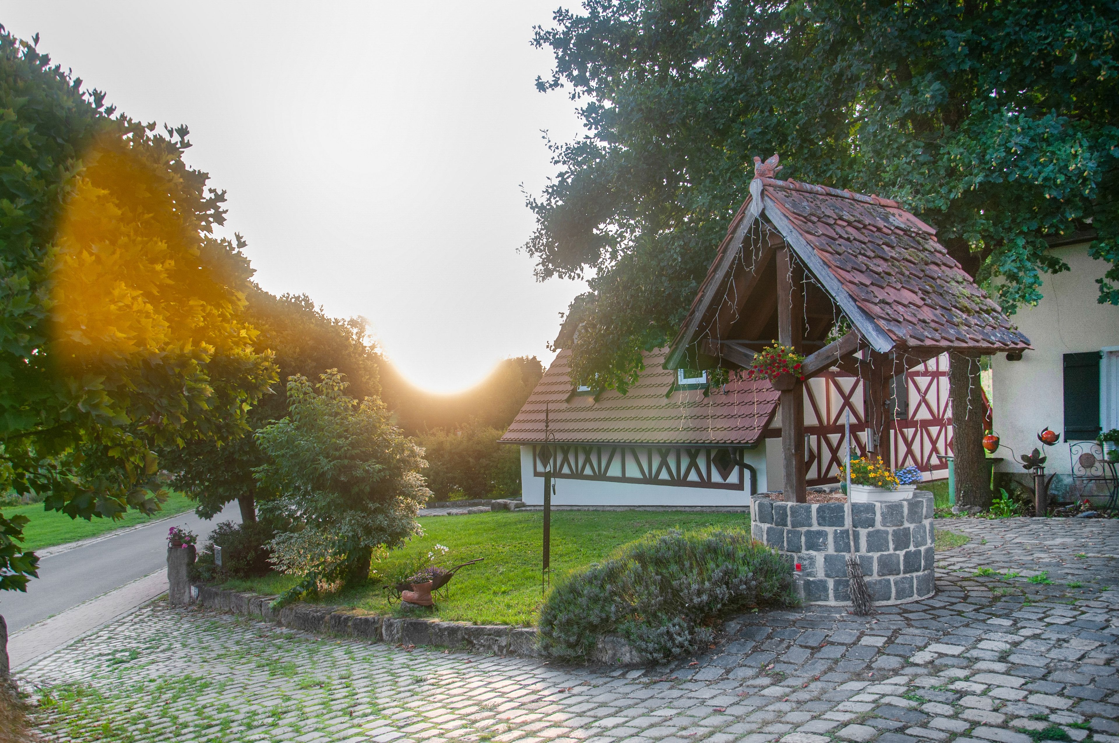 Une construction traditionnelle en bois, dotée d’un toit en tuiles et entourée d’un jardin bien entretenu, agrémenté d’un chemin pavé.