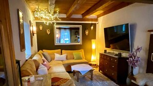 A cozy living room with a sectional sofa, a coffee table, a TV, and a fireplace.