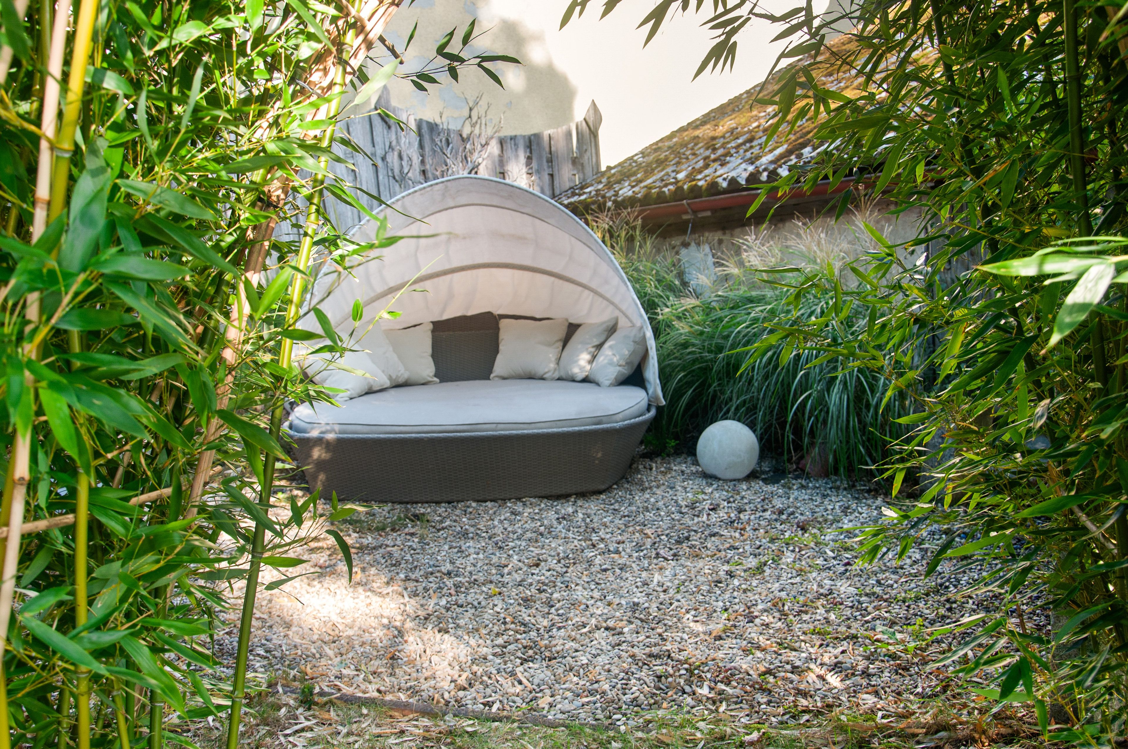 Ein Garten mit einem runden Sitzbereich, umgeben von Bambus und anderer Bepflanzung.