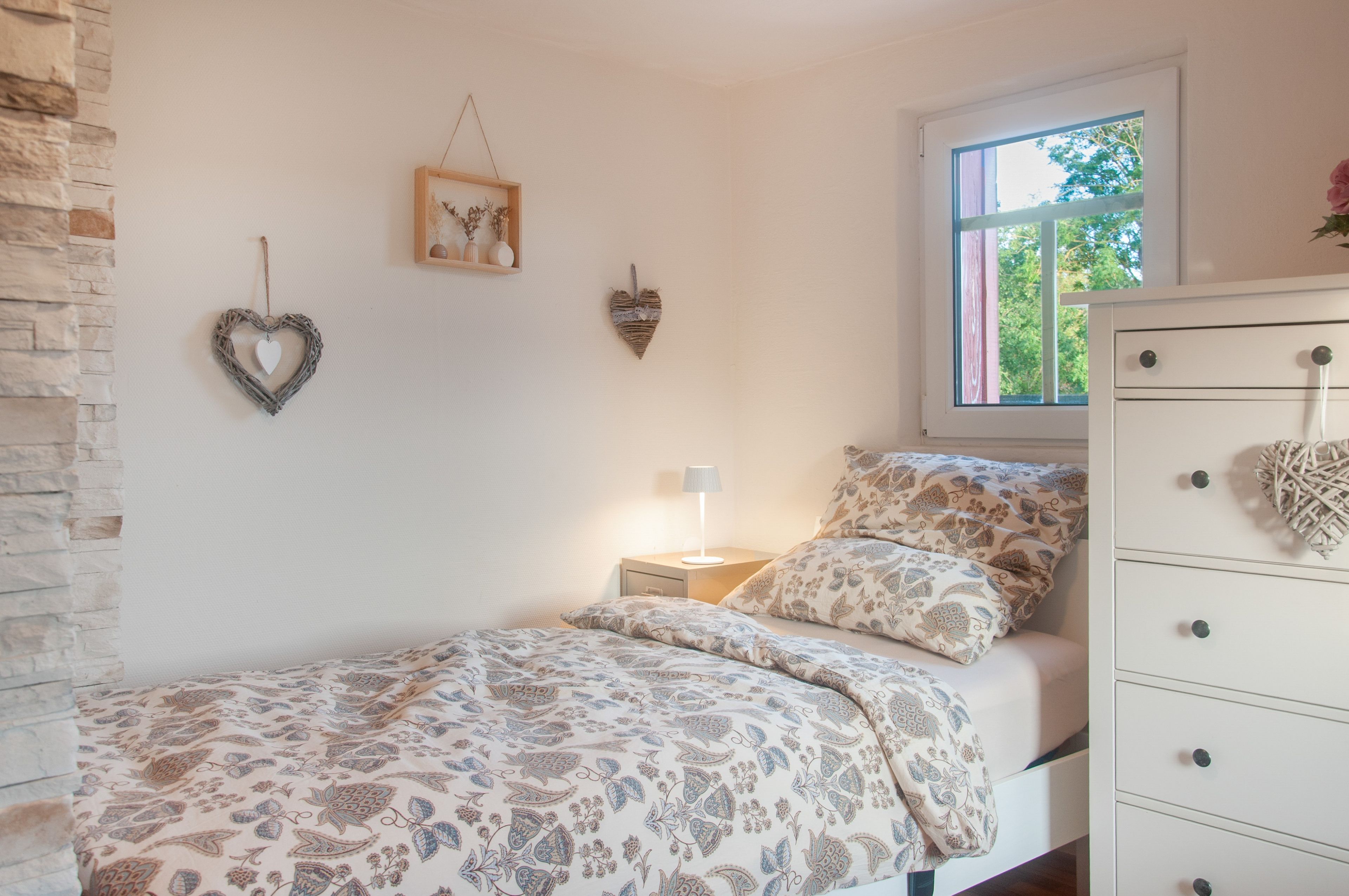 Ein Schlafzimmer mit Bett, Kommode, Nachttisch, Lampe und Wanddekoration.