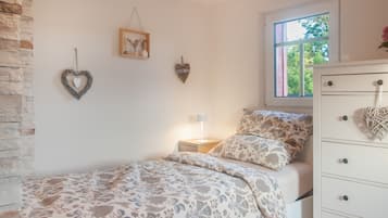 Una camera da letto con un letto, una cassettiera, un comodino, una lampada e decorazioni a parete.