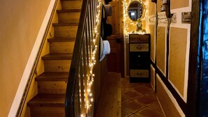 A wooden staircase with a handrail, a mirror with lights, and a small dresser with drawers.