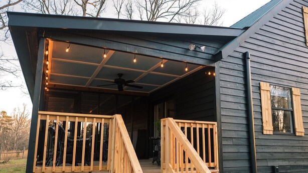 A wooden cabin with a covered porch, a staircase, and a ceiling fan. - Grace Farmhouse-12 ac,  hot tub, fire pit (Menlo)