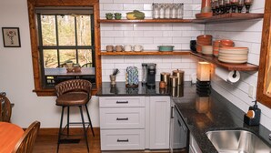 A kitchen with white cabinets, a wooden countertop, a coffee maker, and various kitchenware. - Grace Farmhouse-12 ac,  hot tub, fire pit (Menlo)