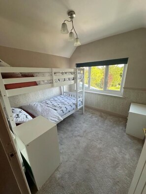 A dorm-style room with bunk beds, a window with a view of greenery, and a ceiling light fixture. - Family Cottage - Alton Towers Peak District , pet Friendly (Ashbourne)