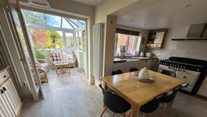 Una cocina con mesa y sillas de madera, una estufa y una ventana con vistas a un jardín.