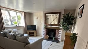 Un salón amplio con sofá, televisión, chimenea y un ventanal grande.