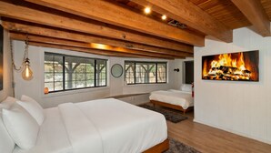 A bedroom with two beds, wooden beams, large windows, and a fireplace. - Walk to Bear Mountain Slopes! Hot Tub Game Room! Fire Pit! Super cute! (Big Bear Lake)