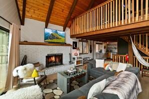 Ein gemütliches Wohnzimmer mit Kamin, einer Couch, einem Couchtisch und einer Hängematte.