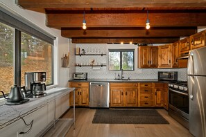 Eine moderne Küche mit Holzausstattung, Edelstahlgeräten und einem großen Fenster.
