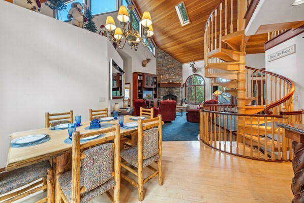 A spacious dining area with a wooden table and chairs, a fireplace, and a spiral staircase. - Private Hot Tub, Game Room, 3,450 sq ft, Beautiful Home! Close to Everything (Big Bear City)