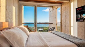 Une chambre avec un grand lit, une vue sur la mer et un écran pour regarder Netflix.