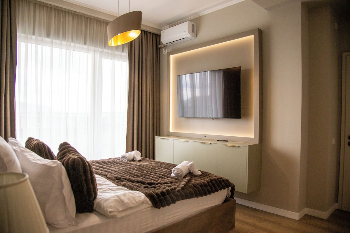 Une chambre d’hôtel moderne dotée d’un grand lit, d’un téléviseur à écran plat fixé au mur et d’un climatiseur installé au plafond.