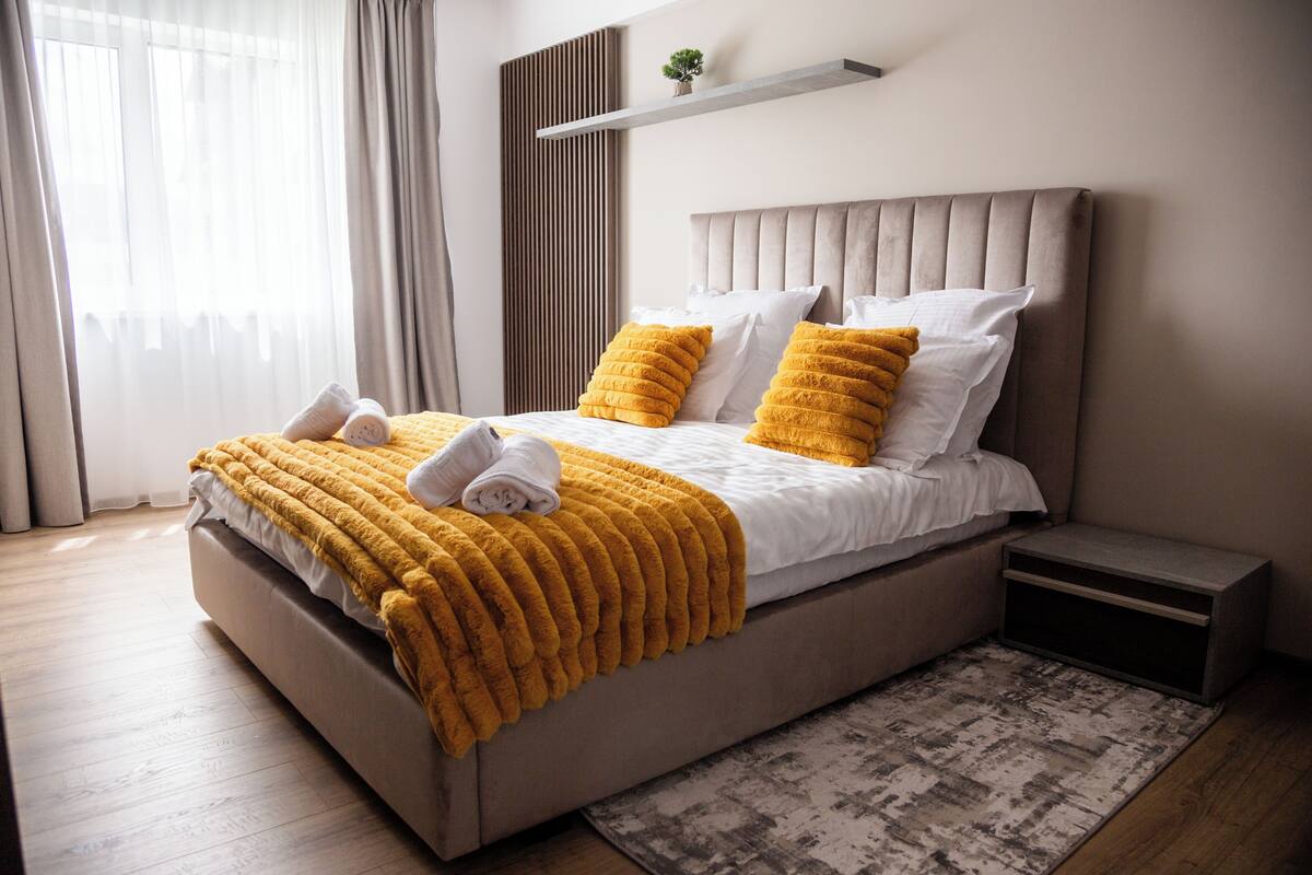 Une chambre à coucher moderne avec un grand lit, une table de chevet et une petite étagère au-dessus du lit.