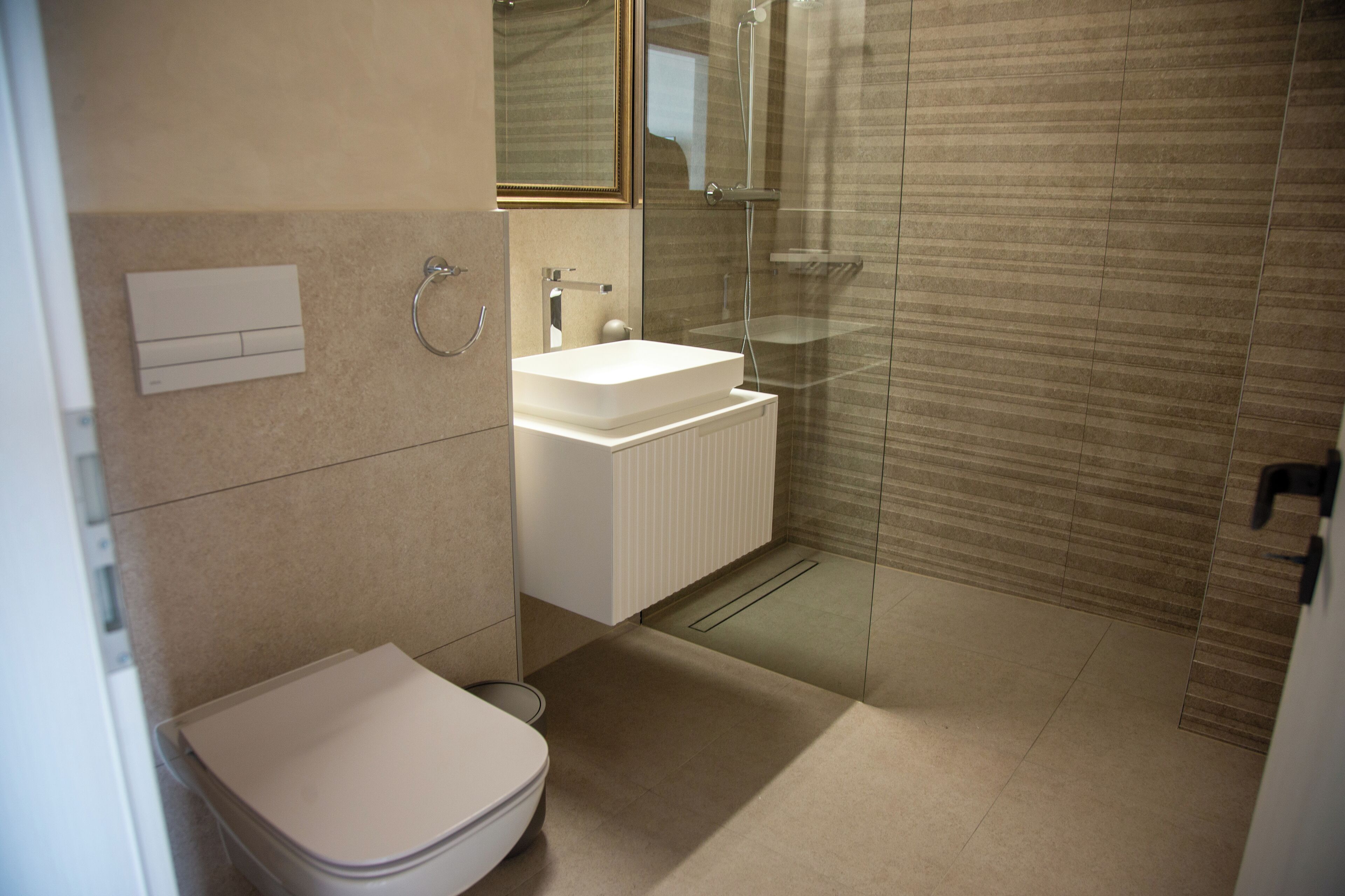 A modern bathroom with a toilet, sink, and glass shower enclosure.
