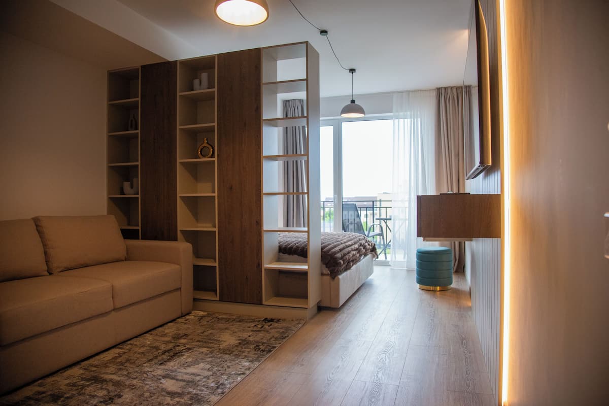 Une chambre moderne avec un canapé, des étagères intégrées, un lit et une vue sur l’extérieur.