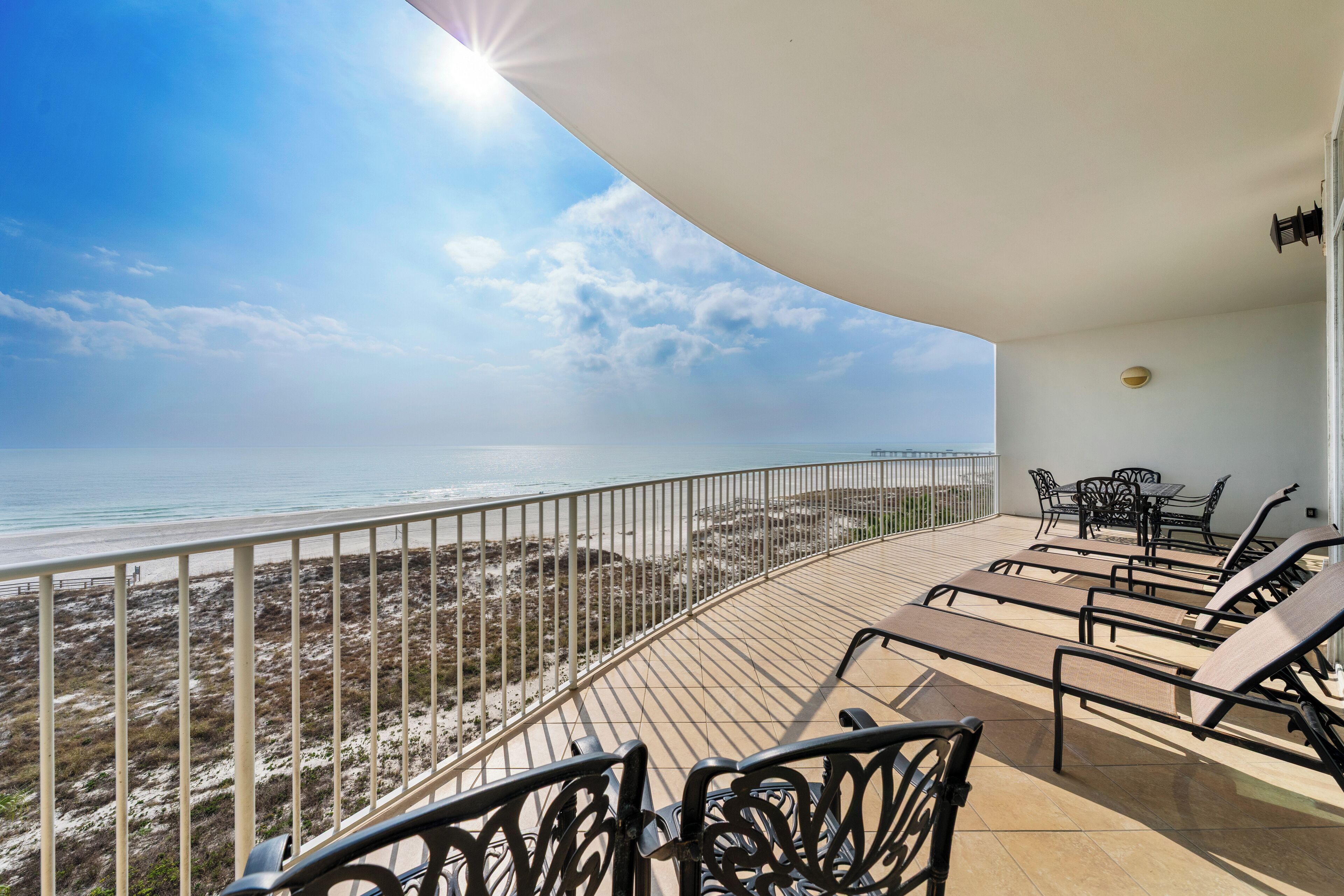 A balcony with sun loungers overlooking a beach.