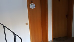 A hallway with two wooden doors, a welcome mat, and a staircase with a handrail.