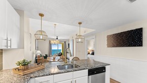Et moderne køkken med granitbordplader, rustfrie stålapparater og hængende lamper.