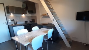 A compact kitchen with a dining area, a staircase, and a TV mounted on the wall. - La Louvatière, in the heart of the village, the ideal place to discover the Monts Jura. (Mijoux)