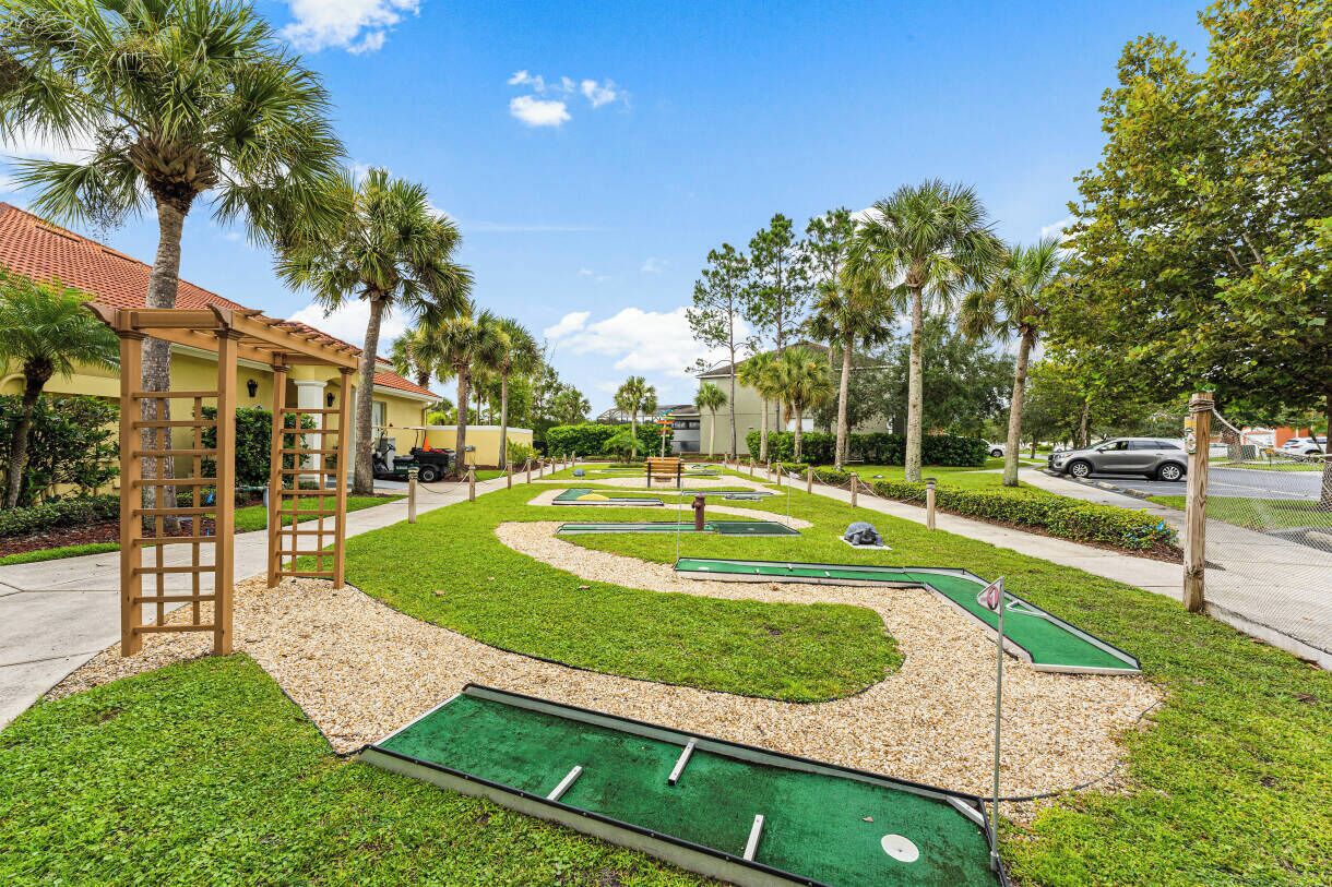 A golf course with a wooden pergola, palm trees, and a clear sky.
