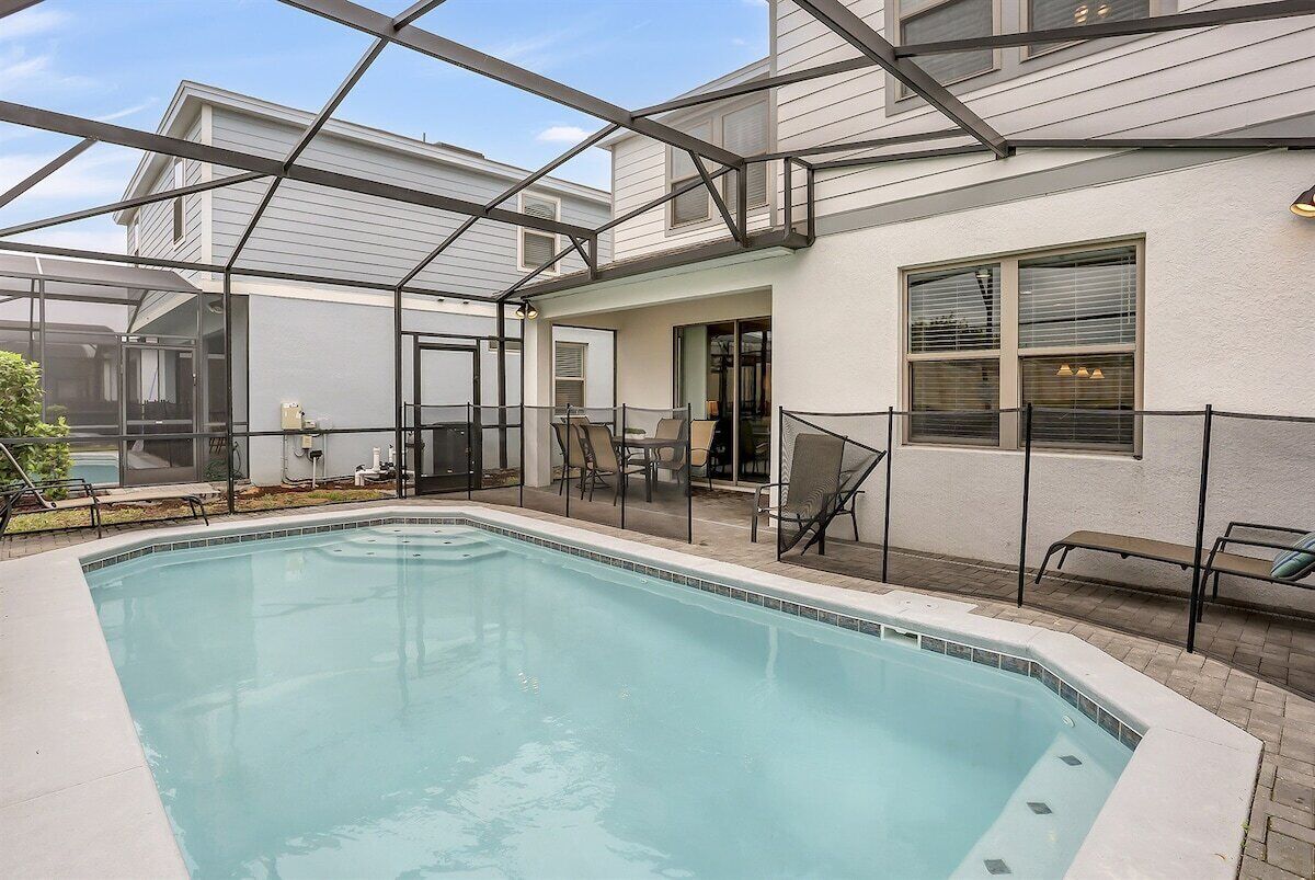 A swimming pool with a glass enclosure, surrounded by outdoor seating and a covered patio area.