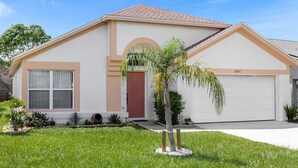 Einbungalow mit roter Tür, beige Fassade und Garage.